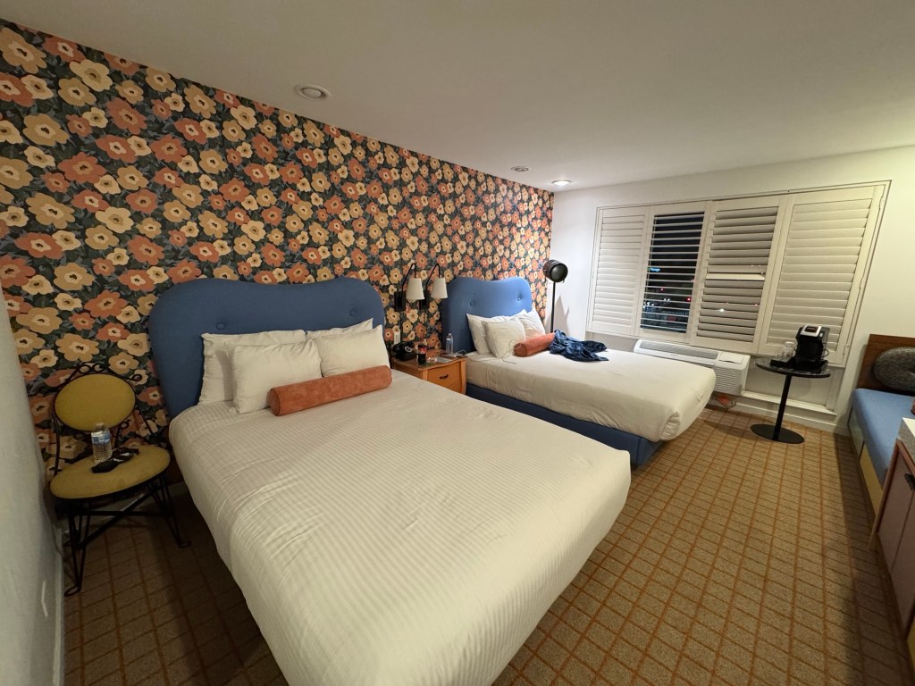 Inside of a hotel room, but 2 double beds and chic floral wallpaper