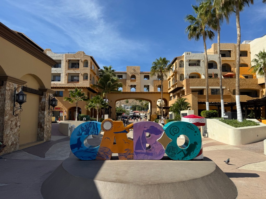 Colourful Cabo sign with buildings and palm trees in background