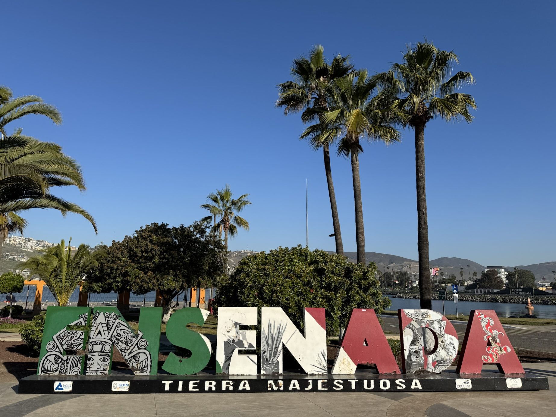 Ensenada sign with palm trees in background