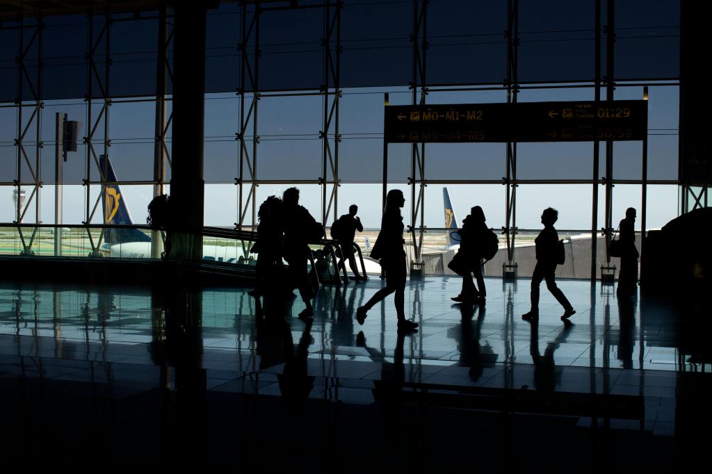 People walking through an airport terminal with planes in the background