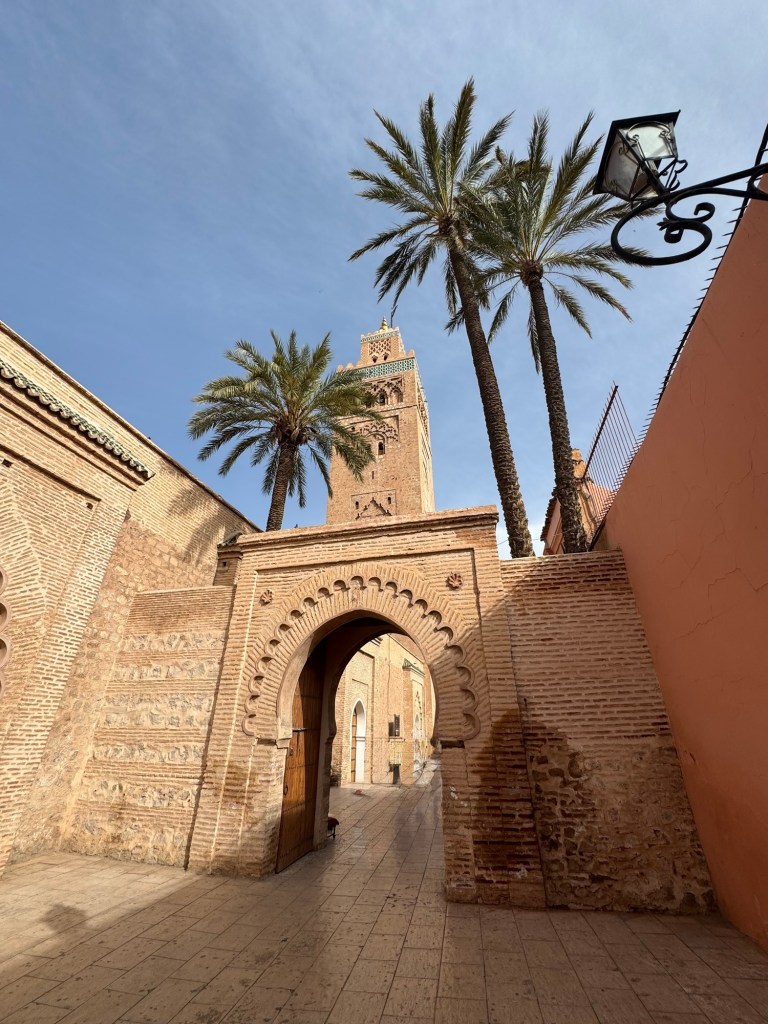 Gates of a mosque, with palm trees and towers in the background
