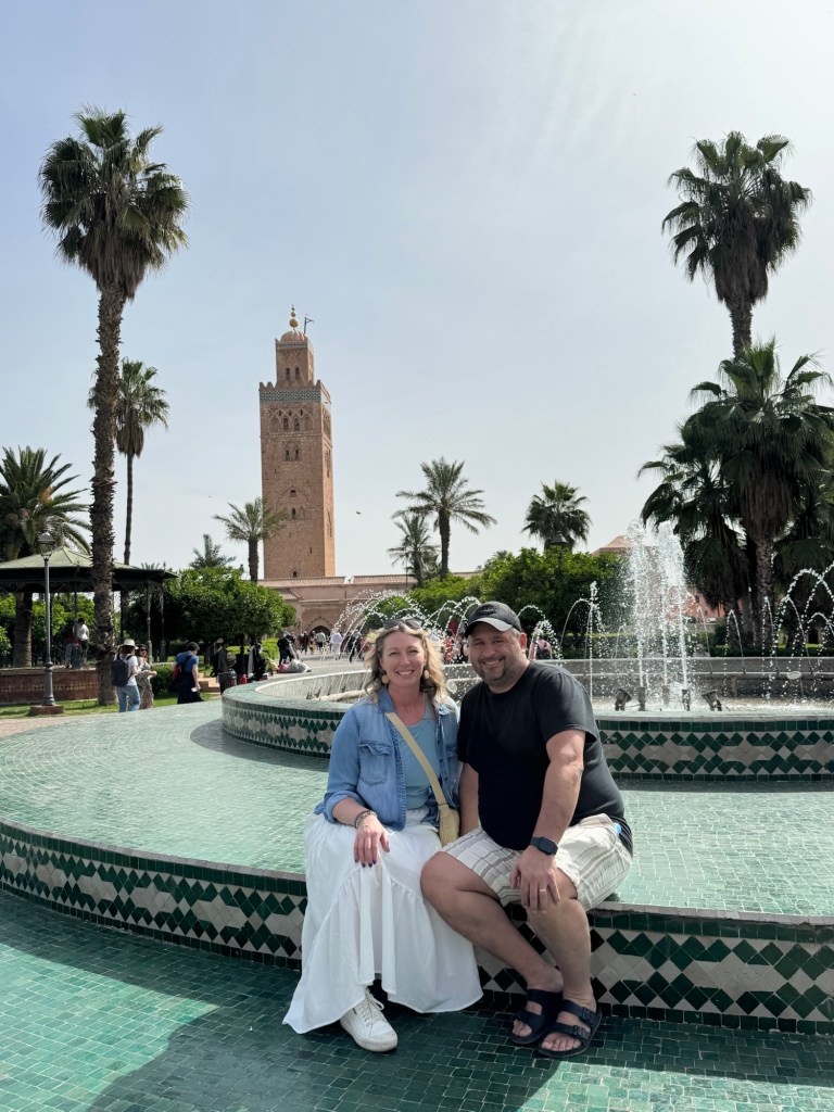 Couple sitting in front of a fountain with tower and palm trees in the distance