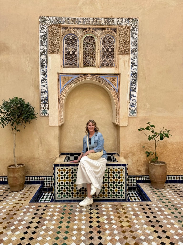 Woman sitting in front of a fountain surrounded by ornate tile work