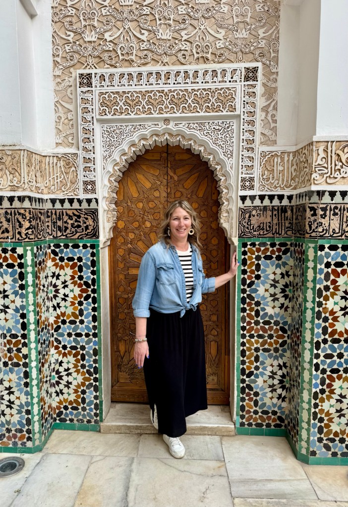 Woman exiting an ornate wooden door surrounded by beautiful tilework