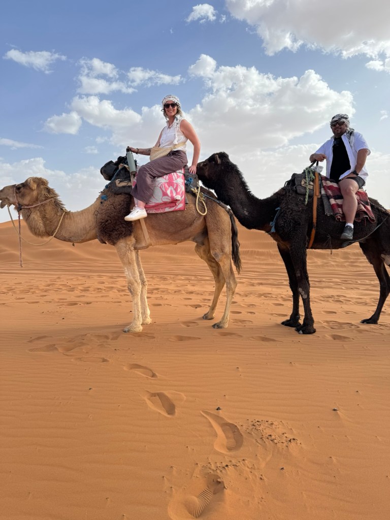 Man and woman sitting atop camels in the desert