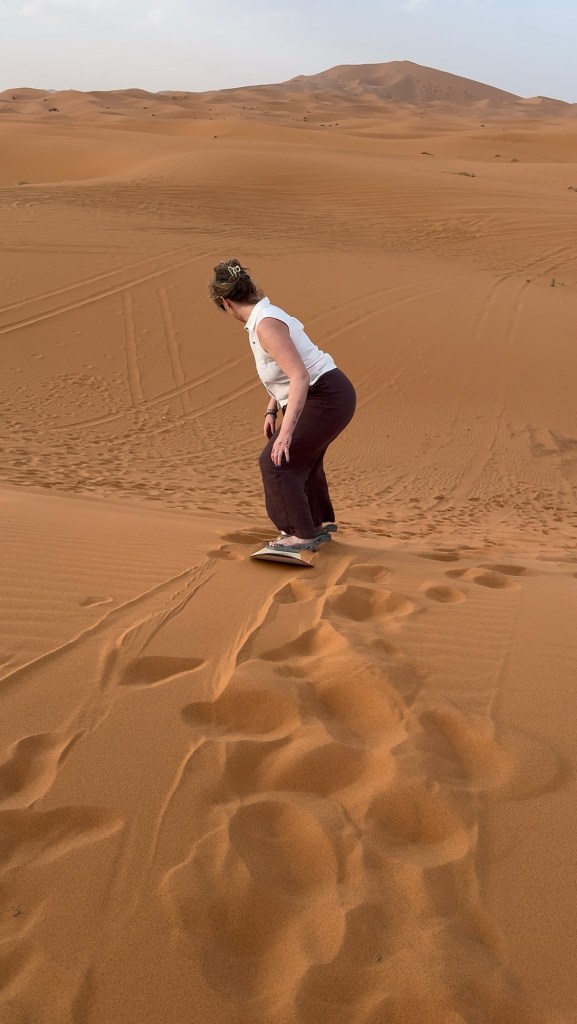 Woman sandboarding down a dune