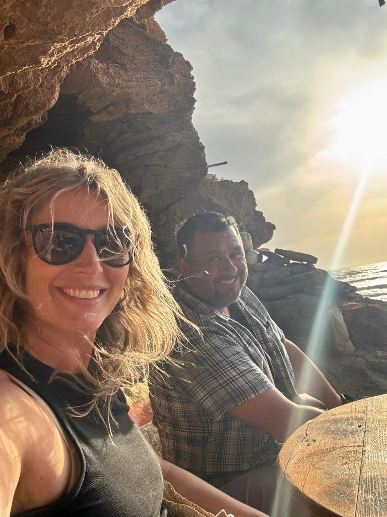 Man and woman sitting in a cave by the ocean